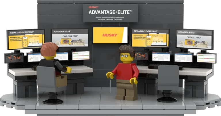 Lego control room with two workers at desks monitoring multiple screens displaying husky advantage elite dashboards and graphics.