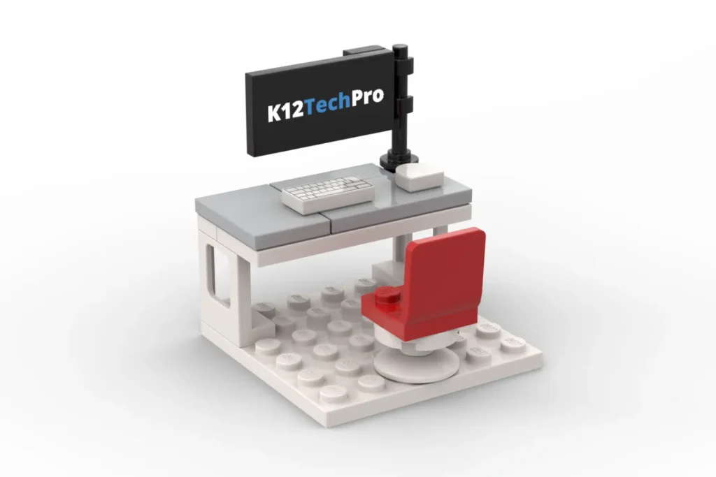 Lego desk setup with a monitor showing k12techpro, keyboard, and a red chair.